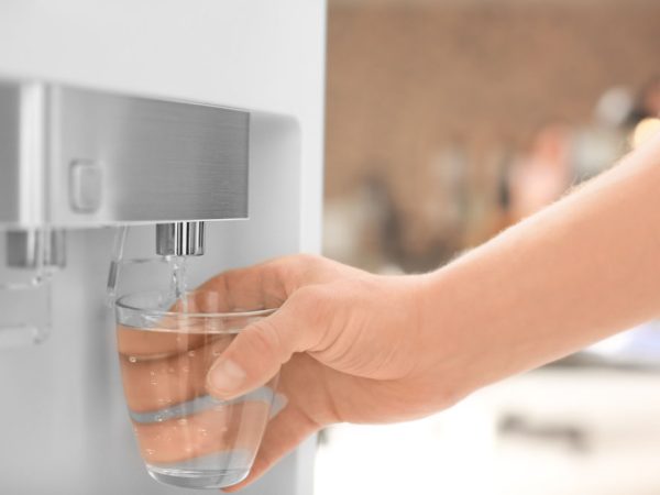 Man filling glass from water cooler, closeup